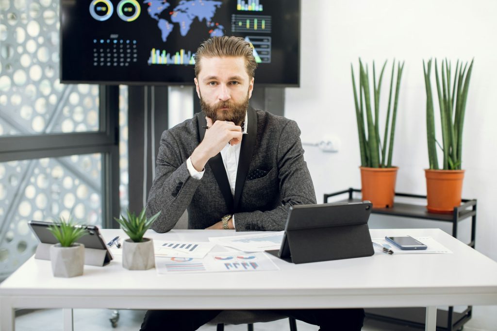 Handsome purposeful confident bearded businessman, chief executive officer in formal wear, sitting
